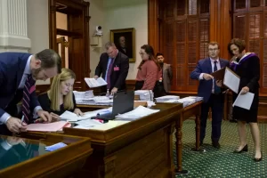 Senate clerks and staff working at desks in the Texas Senate chamber.