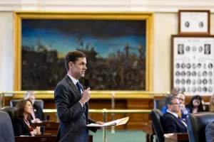 Texas State Senator Mayes Middleton speaking into a microphone on the floor of the Texas Senate