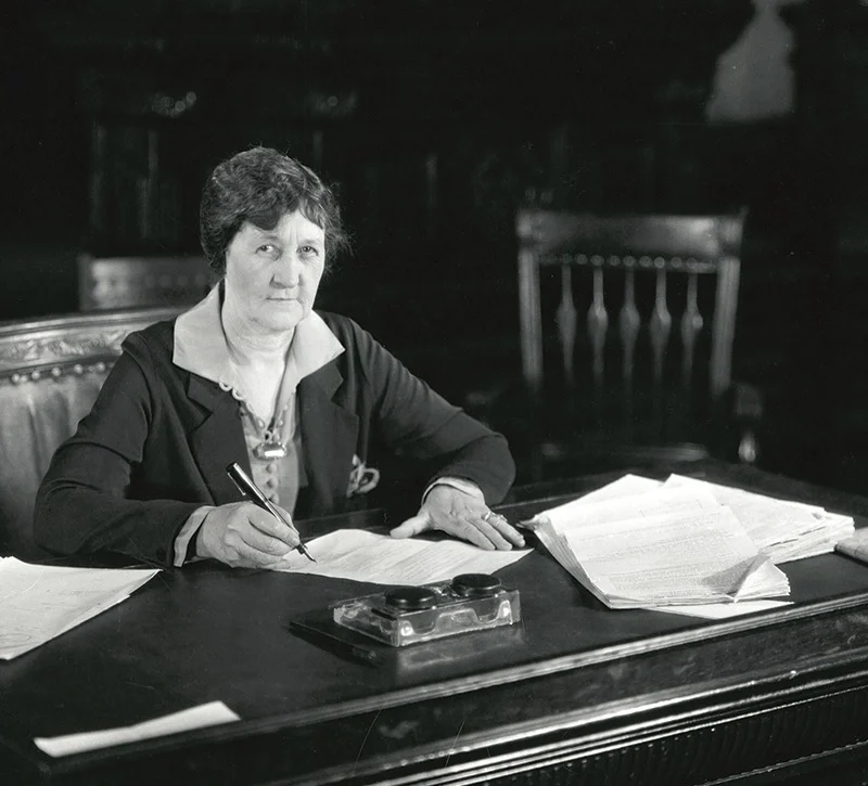 Texas Governor Miriam Ferguson seated at her desk with papers and pen.