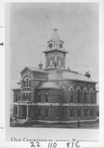 Black and white photography of two-story Old Fort Bend County Courthouse, topped by a cupola.