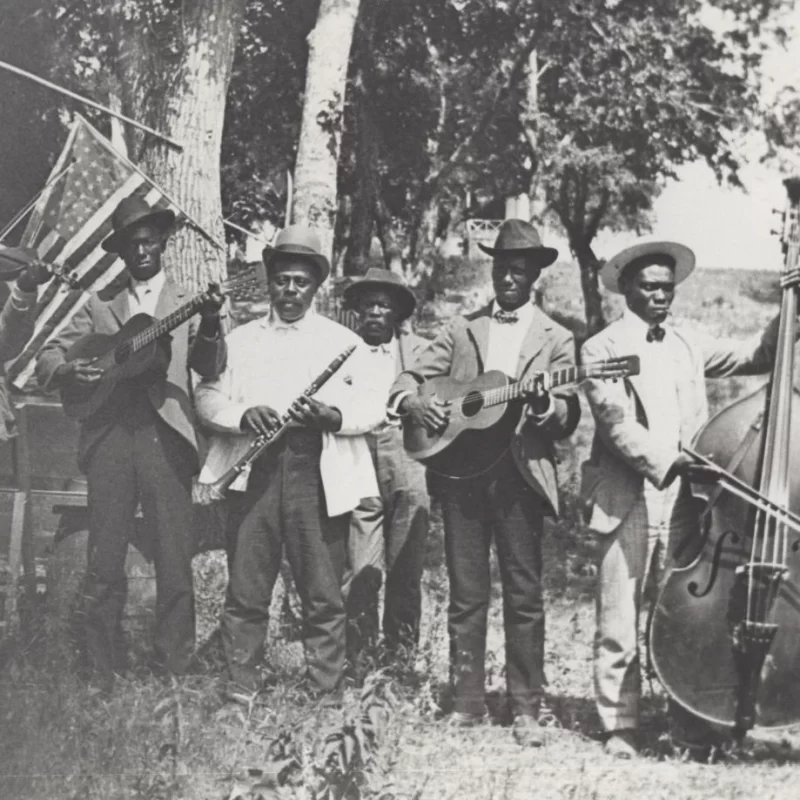 Juneteenth band with two guitars, clarinet, fiddle, and bass, photographed in 1900 in East Austin, Texas.