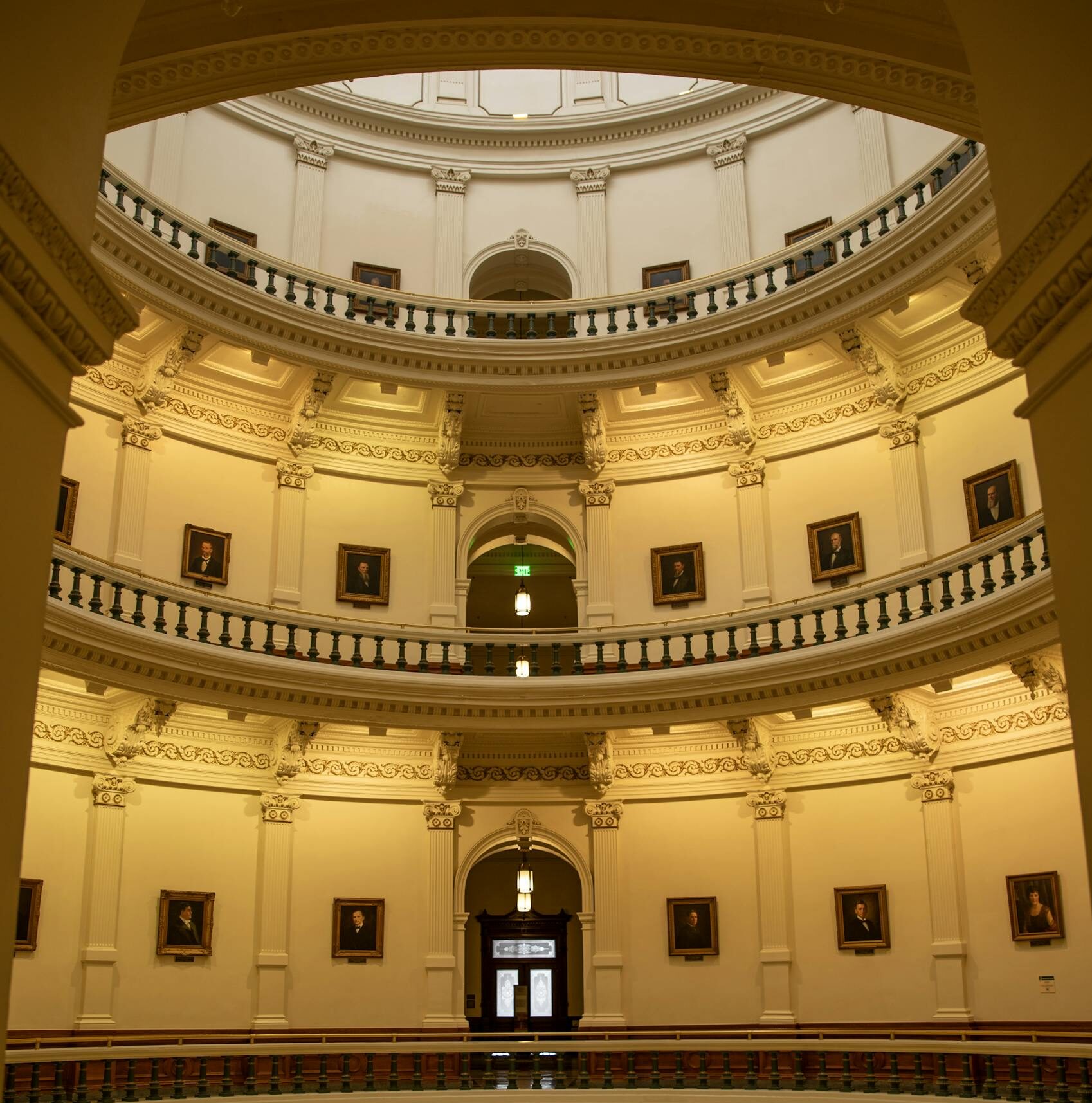 A vertical shot of the neoclassical interior of the Texas State Capitol rotunda featuring balustrades and symmetry.