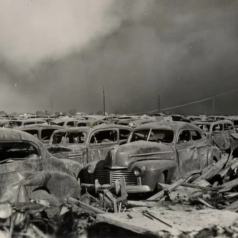 A parking lot full of cars with their windows blasted out and heavy damage, after the Texas City explosion of 1947.